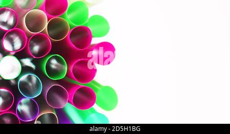 Insolita vista dall'alto di molti cocktail tubes isolati multicolore in plastica su sfondo bianco. Cannucce da bere di colori al neon brillanti. Effetto luce Foto Stock