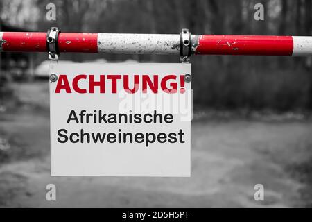 Segno con l'iscrizione 'Achtung Afrikanische Schweinepest' (Attenzione peste suina africana) su una barriera Foto Stock