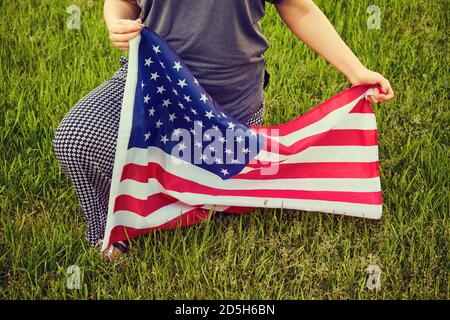 Protesta nel parco americano erba, donna inginocchiato. Bandiera degli Stati Uniti, inginocchiati su sfondo verde Foto Stock