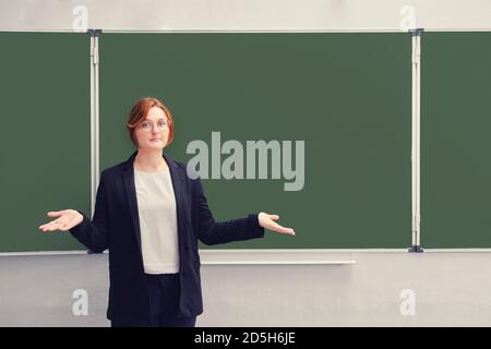 L'insegnante spalma le mani vicino alla lavagna vuota della scuola, copia spazio per il testo. Concetto di problemi con l'educazione dovuta al coronavirus epideremi Foto Stock