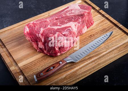 Manzo disossato Chuck Roast su un tagliere con un coltello da intaglio in cucina Foto Stock