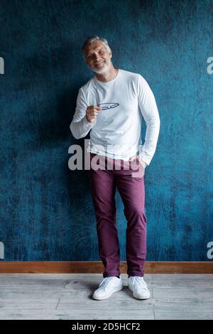Casual Grigio-capelli mature bel ritratto uomo su sfondo blu scuro parete. Foto Stock