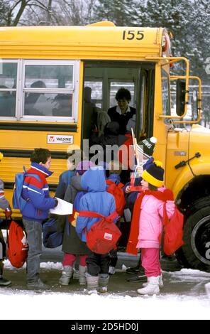 Pattuglia elementari boy supervisiona la salita a bordo di un bus di scuola da parte degli studenti Foto Stock