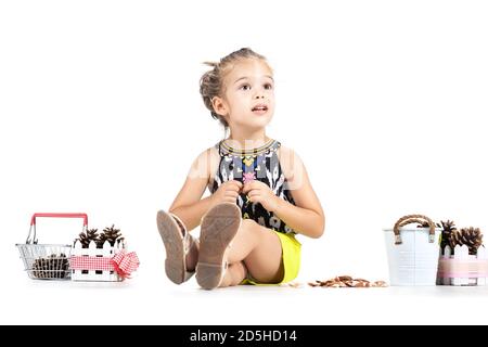 piccola ragazza caucasica che gioca con i pinecones Foto Stock