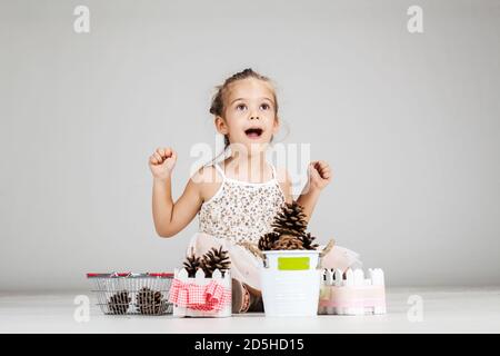 piccola ragazza caucasica che gioca con i pinecones Foto Stock