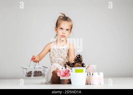 piccola ragazza caucasica che gioca con i pinecones Foto Stock