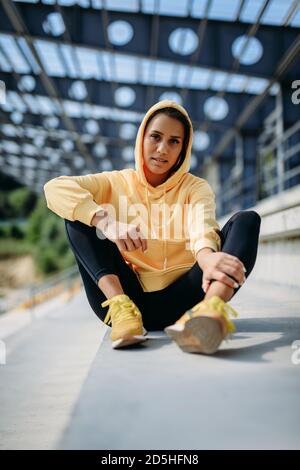 Donna rilassata in abbigliamento sportivo seduto sulle scale dopo l'allenamento Foto Stock
