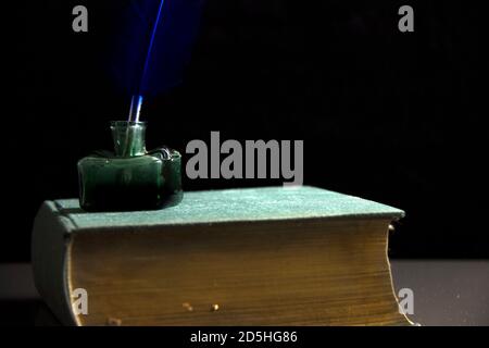 Penna piuma con inchiostro e vecchio libro. Sfondo vintage. Foto Stock