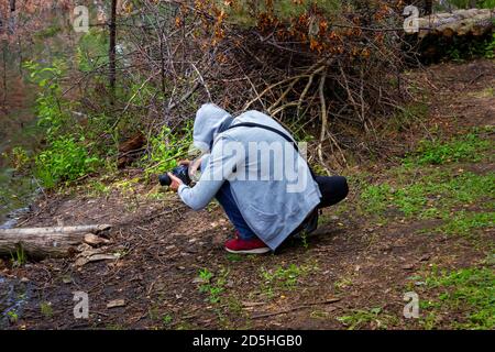 Un giovane scatta un video con una reflex in natura nella foresta vicino al lago. Foto Stock