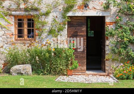 Esterno di un vecchio edificio rurale tradizionale decorato con piante e fiori Foto Stock