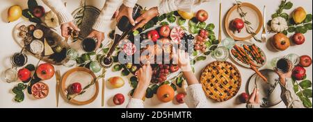 Le mani dei popoli celebrano la festa del Ringraziamento sopra il tavolo decotato dell'anatra arrostita Foto Stock