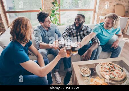 Ritratto di quattro simpatici allegri e allegri amichevoli incontri di ragazzi birra di clinking trascorrere il fine settimana di tempo libero al loft industriale stile Foto Stock