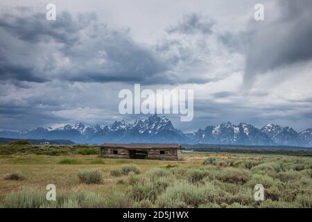 La vecchia cabina storica del ranch di Cunningham nel Grand Teton National Park fu costruita con tronchi da J.P Cunningham nel 1888. Dietro si trova il Grand Teton e il Teton Foto Stock