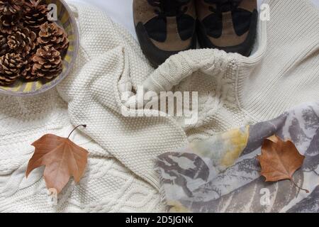 Direttamente sopra il colpo di maglione bianco, sciarpa, scarpe, cono di pino e foglie d'autunno Foto Stock