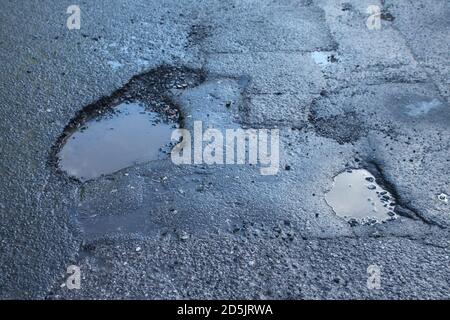 Buche in asfalto, asfalto superficie UK Foto Stock