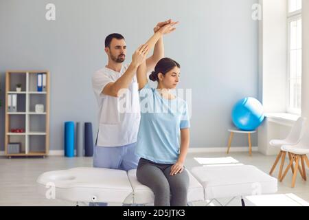 Chiropractor autorizzato o fisioterapista che aiuta la giovane paziente femminile in moderno clinica Foto Stock