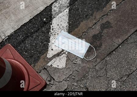 La maschera chirurgica usata è stata lasciata sulla strada Foto Stock