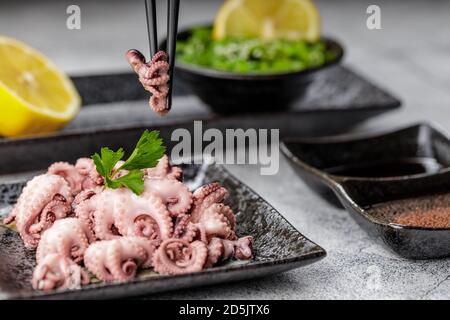 Tradizionale giapponese o concetto di pesce. Mini polpo bollito delizioso e sano e insalata di wakame o alghe con salsa di soia e limone serviti con Foto Stock