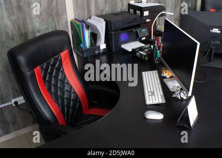 Posto di lavoro al tavolo in ufficio con computer, mouse bianco, tastiera, monitor e grande sedia in pelle. Spazio personale in camera per lavorare. Documenti, calcul Foto Stock