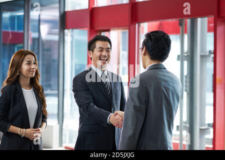 i dirigenti aziendali asiatici scuotono le mani con i clienti in visita in ascensore hall di un moderno edificio per uffici Foto Stock