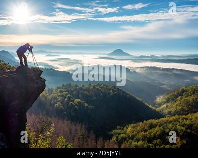 Fotografo in montagna strega attraverso il mirino. Fotografo della natura che scatta foto del bellissimo paesaggio mattutino dalla cima della montagna Foto Stock