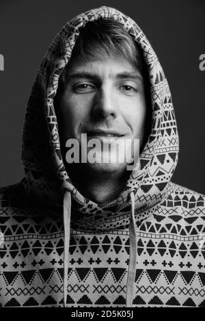 Felice uomo bello che indossa felpa con cappuccio su sfondo grigio Foto Stock