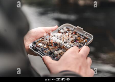 Pescatore che tiene la scatola dei lures di pesca del mosca nelle mani. Foto Stock