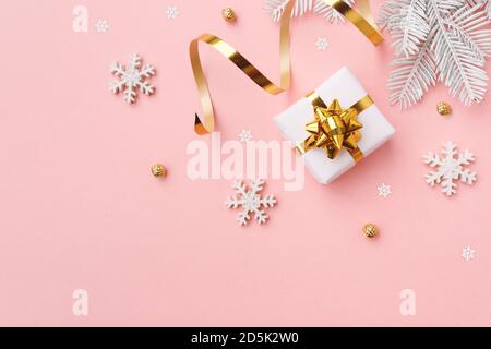 Regalo di Natale con fiocchi di neve e decorazione su sfondo rosa pastello Foto Stock
