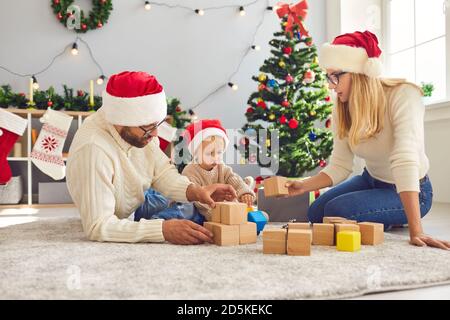 La giovane famiglia trascorre le vacanze di Natale a casa e gioca insieme in un accogliente soggiorno Foto Stock