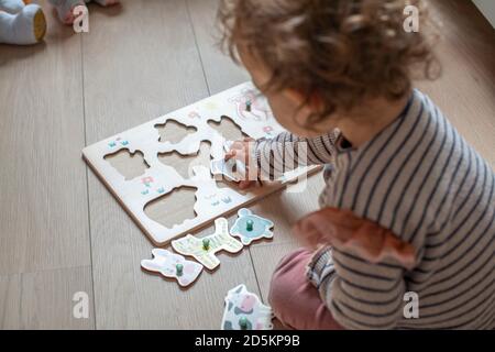 bambino di 17 mesi che gioca con un puzzle di legno, forme adattate di animali Foto Stock