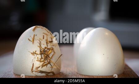 Tre uova fresche di galline ricoperte di paglia in un supporto di legno di fronte in cucina. Gli ingredienti di fondo scuro del cibo producono un'alimentazione sana. Foto Stock