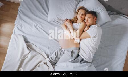 Felice giovane coppia dormendo insieme nel letto, Sweet Loving giovani persone che si tiene a vicenda mentre dormono. Bella Donna è incinta, amorevole Foto Stock