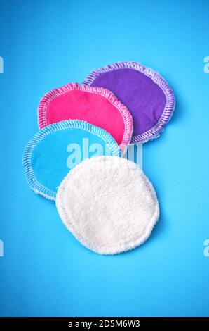 Quattro tamponi di pulizia riutilizzabili in cotone organico lavabili senza sprechi per rimodella rimozione in bianco viola blu e rosa su sfondo blu pastello Foto Stock