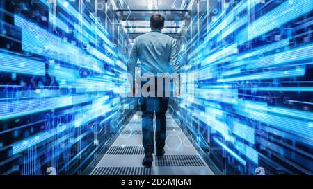 Foto di un giovane specialista IT che ha guidato il corridoio in un data center funzionante pieno di server rack e supercomputer. Visualizzazione concettuale di Foto Stock