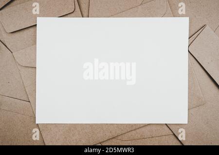 Vista dall'alto della busta di carta marrone con carta bianca. Disposizione piatta di molte buste di carta marrone sovrapposte. Stile minimalista. Foto Stock