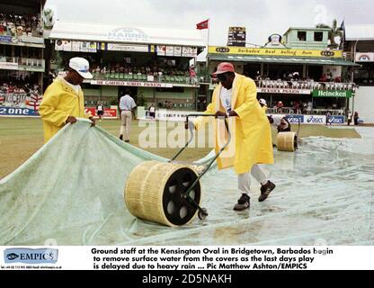 Il personale di terra del Kensington Oval a Bridgetown, Barbados inizia a rimuovere l'acqua di superficie dalle coperture come l'ultimo giorno di gioco è ritardato dovuto la pioggia pesante Foto Stock