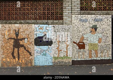 Muro di contenimento decorato con fregio a mosaico trencadís, Střešovičky noto anche come Malé Střešovice (piccolo Střešovice) a Praga, Repubblica Ceca. Střešovičky è un ex insediamento operaio con piccole case risalenti alla fine del 18 ° secolo che ha conservato la sua atmosfera originale intatta attraverso i secoli e conosciuto ora come un sito romantico senza turisti nella periferia di Praga. Il diavolo, un sottomarino e un giardiniere sono raffigurati nel mosaico posto in via Pod Adnělkou. Foto Stock