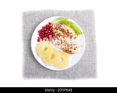 Filetti di pollo fritti con lattuga, ananas e semi di melograno isolati su sfondo bianco, vista dall'alto. Foto Stock
