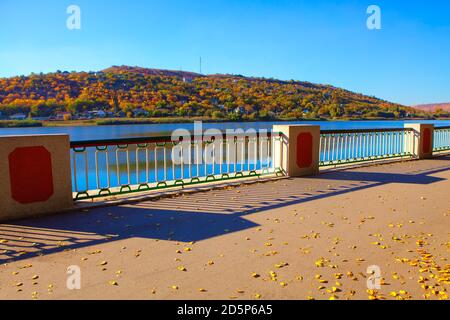 Foglie d'autunno sul lungomare con balaustra Foto Stock