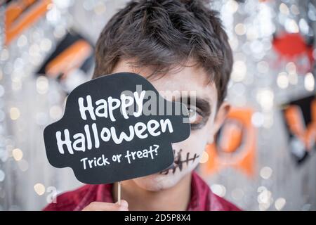 Capretto hloding Halloween stand prop davanti a faccia spooky - concetto di trucco o cura di Halloween. Foto Stock