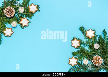 Plastica gratis Natale piatto con decorazione vacanza biologica: Rami di conifere albero, coni di pino, cannella stella biscotti su sfondo blu Foto Stock