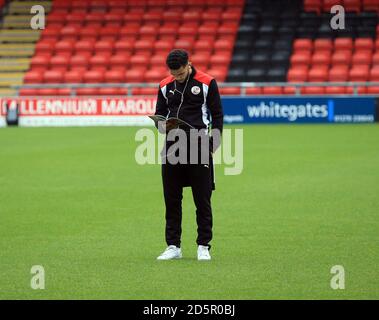 Billy Clifford di Crawley Town legge un programma di partite giornaliere sul campo prima della partita della Sky Bet League due tra Crewe Alexandra e Crawley Town. Foto Stock