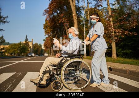 Donna adulta lavoratore di medicina che cammina con l'uomo anziano nel città Foto Stock