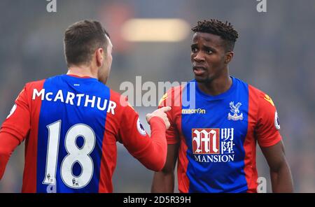 James McArthur di Crystal Palace (a sinistra) sostiene il suo punto di vista verso il compagno di squadra Wilfried Zaha Foto Stock