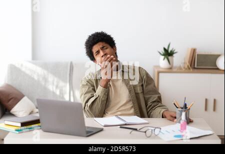 Annoiato studente nero teen yawning durante i suoi studi online a. casa Foto Stock