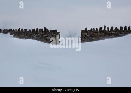 Gap in un muro di pietra in un paesaggio nevoso Foto Stock