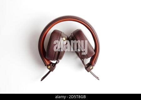 Moderne cuffie wireless ripiegate in pelle marrone isolate su bianco Foto Stock