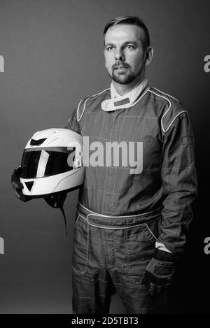 Uomo biondo portatore motociclista con goatee in full gear contro sfondo grigio Foto Stock