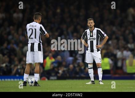 Lo stand Paulo Dybala di Juventus (a sinistra) e Miralem Pjanic si sono sbattuti dopo aver ceduto un secondo goal durante la finale della Champions League 2017 che si è tenuta allo Stadio Nazionale di Cardiff Foto Stock