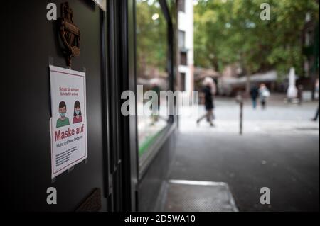 14 ottobre 2020, Nord Reno-Westfalia, Duesseldorf: La gente cammina attraverso la città vecchia di Düsseldorf, mentre un cartello in un ristorante dice 'Mask on'. La pandemia della corona sta diventando sempre più un problema per le grandi città e le agglomerazioni della Renania settentrionale-Vestfalia. Foto: Fabian Strauch/dpa Foto Stock